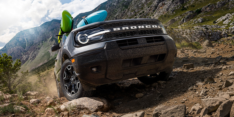 A 2025 Ford Bronco Sport carving up terrain with kayaks strapped to the roof rack in New Hudson, MI