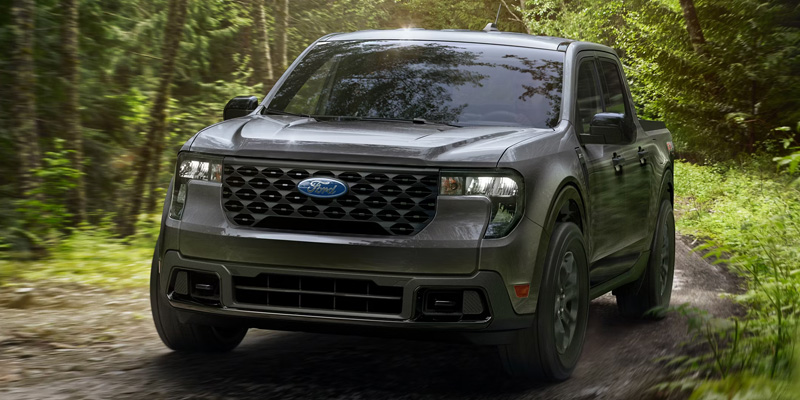 A Ford Maverick driving through a forested trail.
