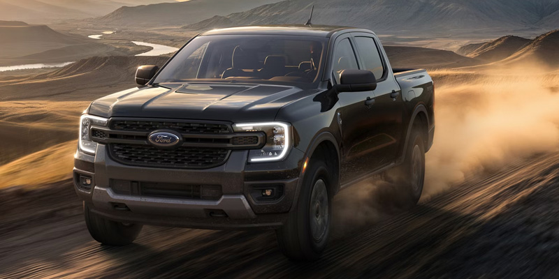 Ford pickup truck driving off-road through a dusty desert landscape, highlighting rugged performance and capability, representing available Ford lease options.