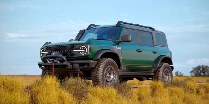 A green Ford Bronco parked in a filled