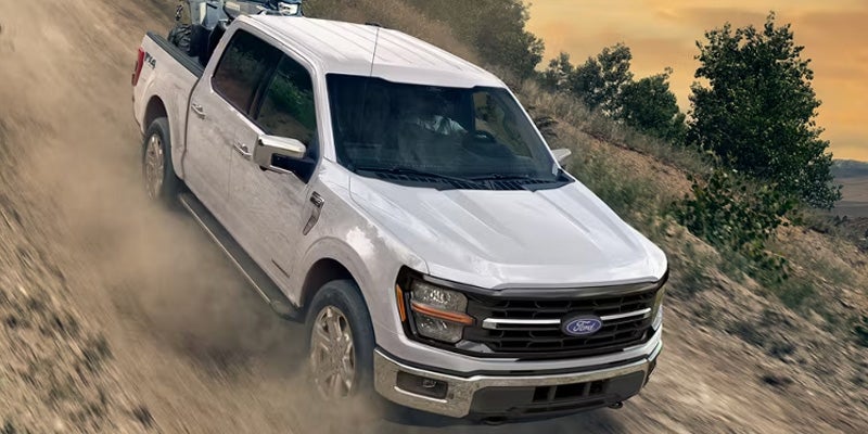 2026 Ford F-150 off-road driving in New Hudson MI descending rugged terrain with advanced suspension and terrain management system capability