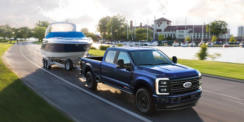 2026 Ford Super Duty towing a boat in New Hudson MI highlighting maximum towing capacity for Michigan lakes, camping trips, and summer recreation