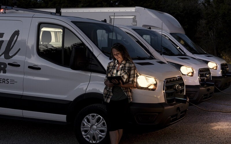 Ford E-Transit fleet of vehicles parked in a row at dusk