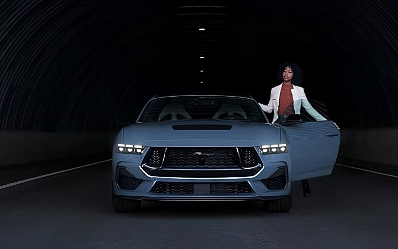 Front view of Ford Mustang parked with driver's door open