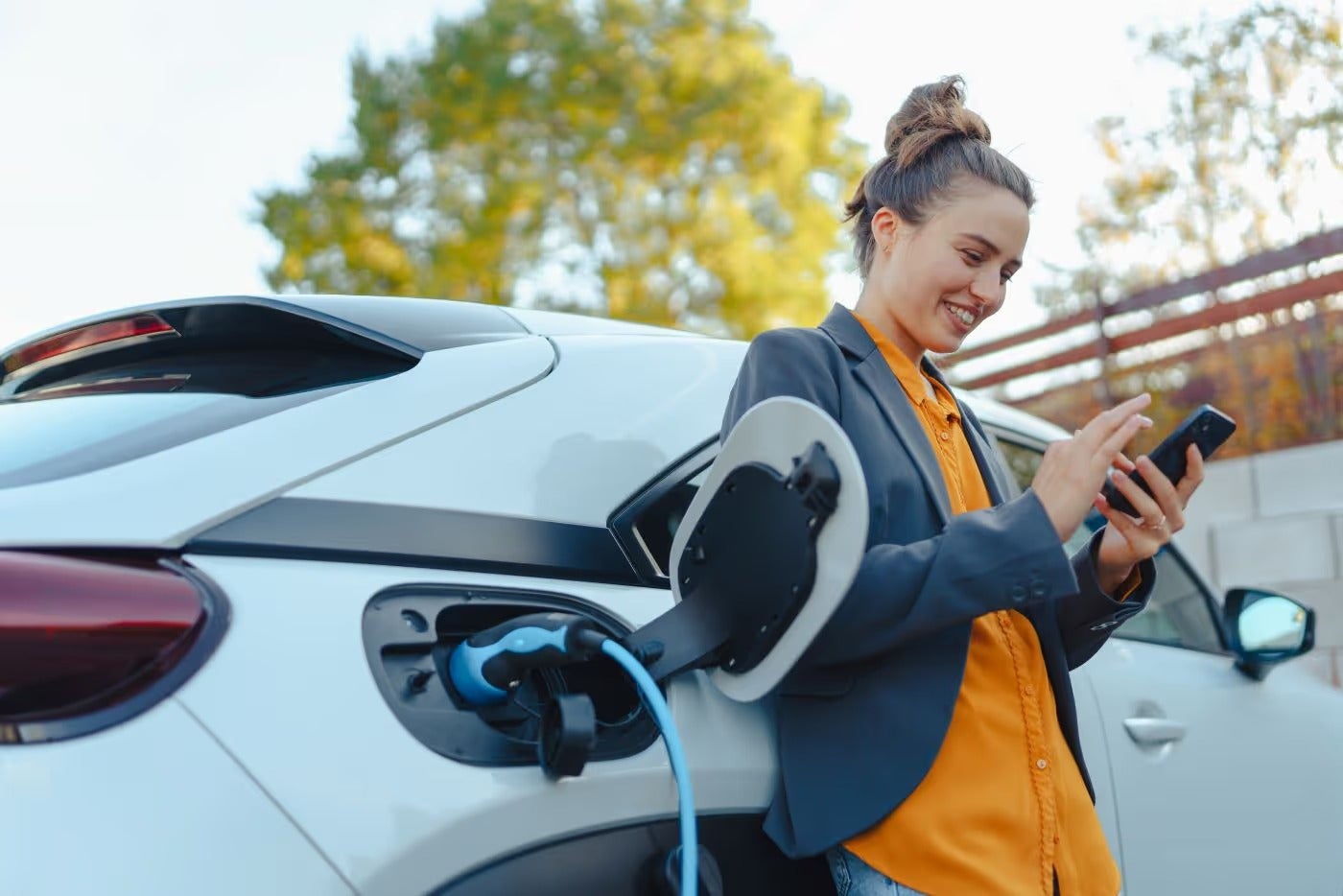 Woman playing with phone while waiting for Ford electric vehicle to charge