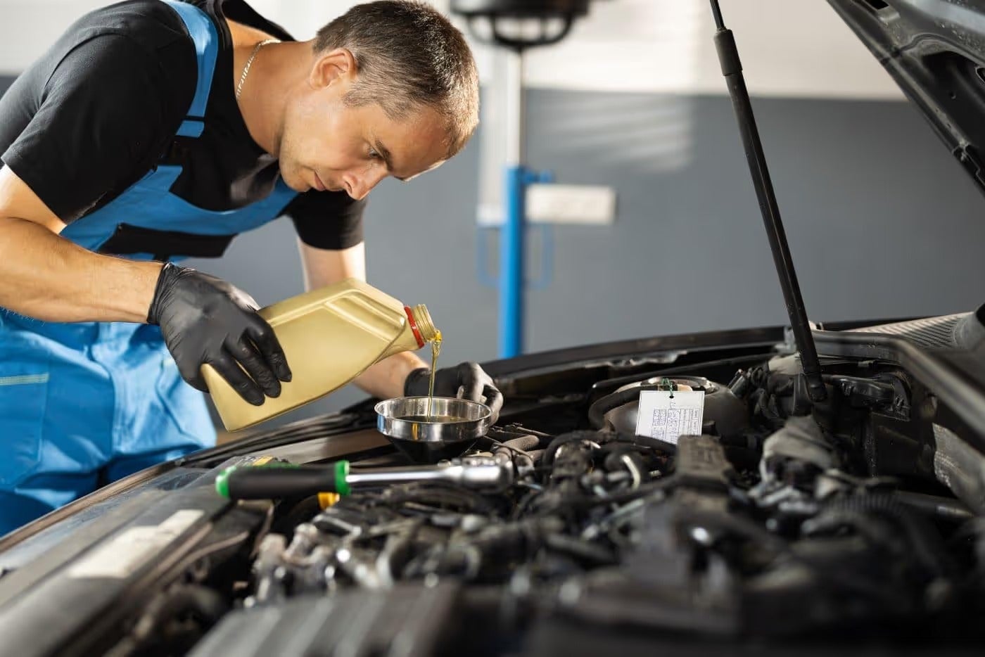 Technician pouring oil into car