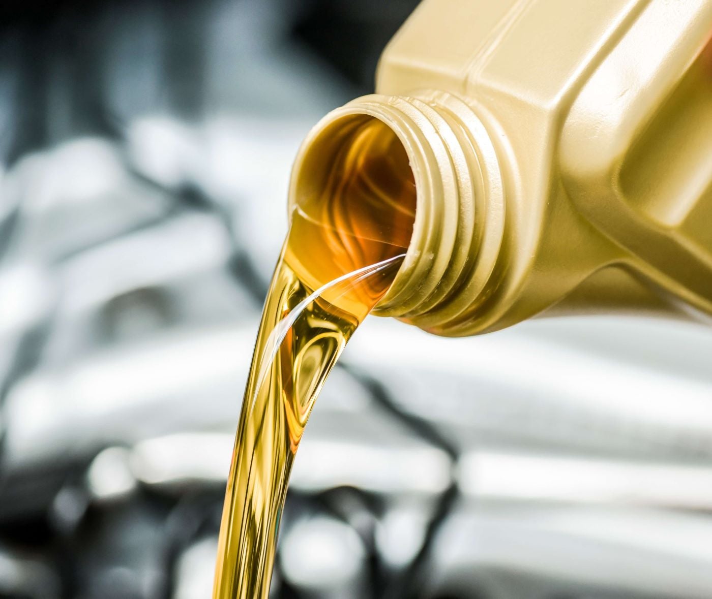 Close up of oil pouring from bottle into vehicle